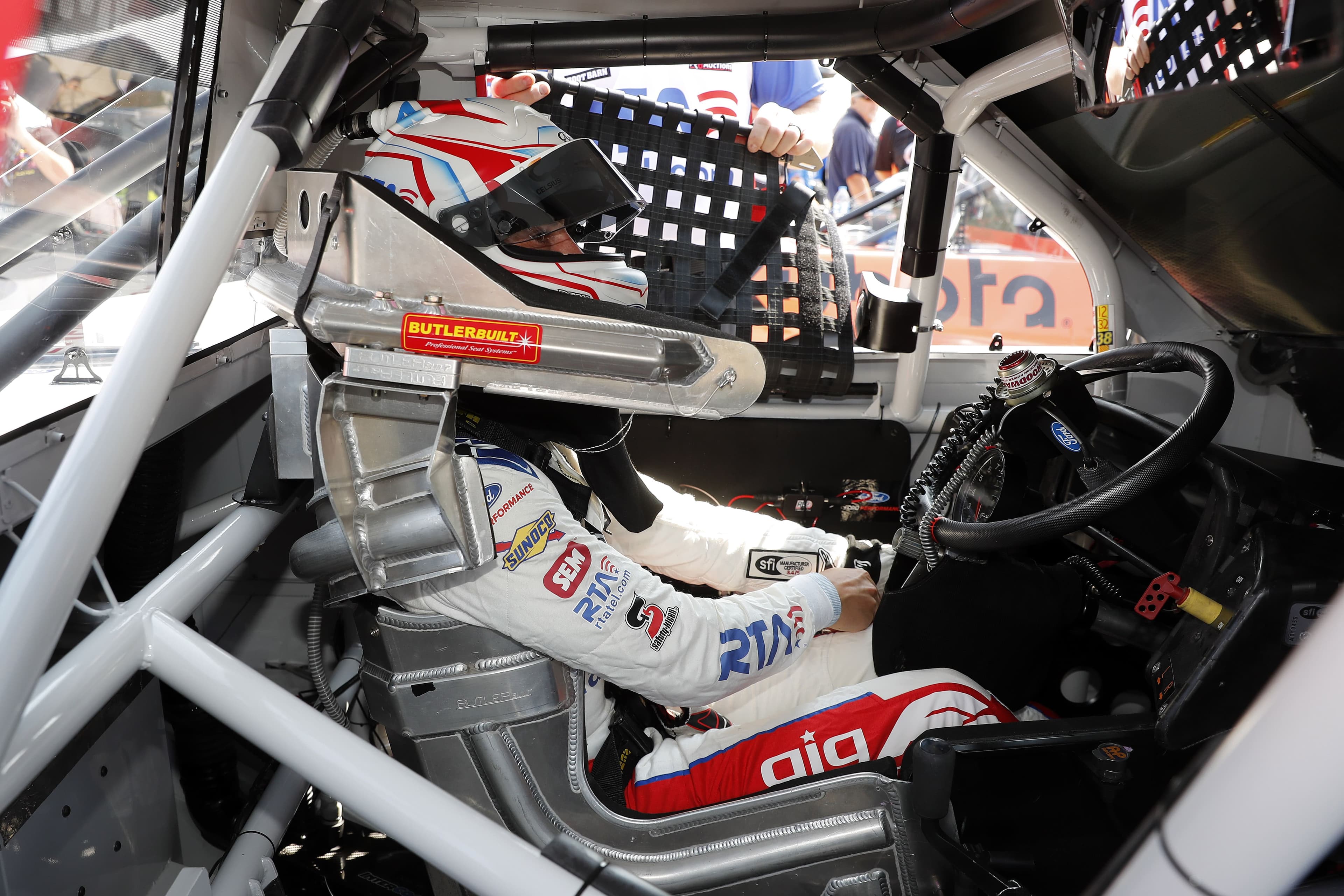 Cockpit interior with Zane Smith in seat wearing helmet, roll cage visible